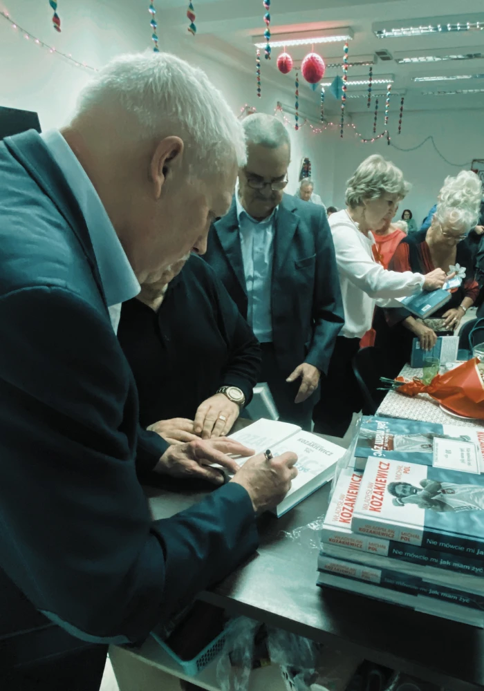 Władysław Kozakiewicz podpisuje książki uczestnikom spotkania